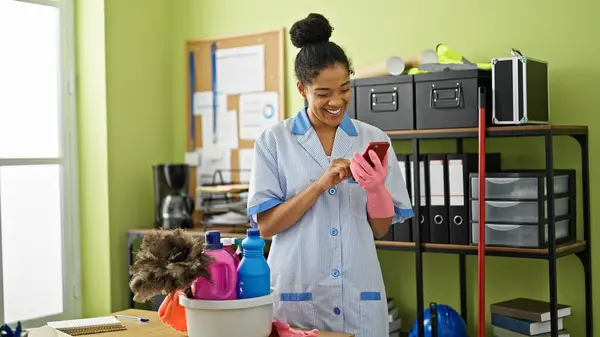 African american woman clean professional using smartphone smiling at office