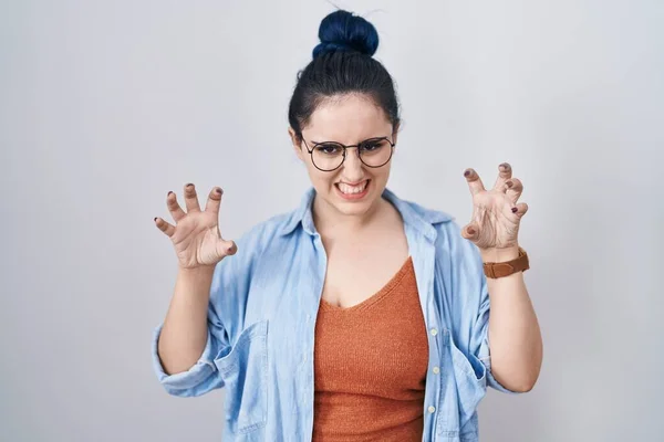 Young modern girl with blue hair standing over white background smiling funny doing claw gesture as cat, aggressive and sexy expression