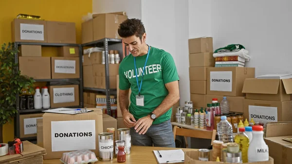 stock image Young hispanic man volunteer holding products speaking at charity center