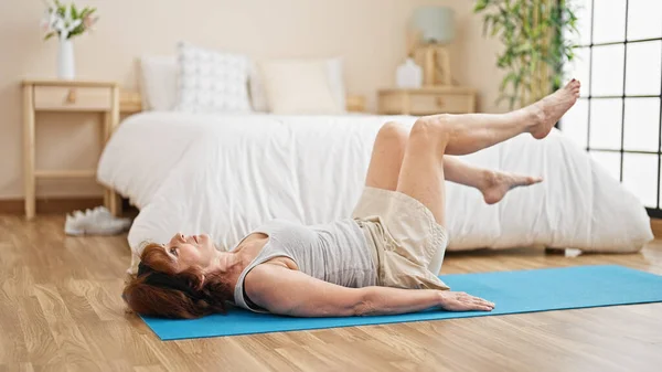 Middle age woman training legs exercise at bedroom