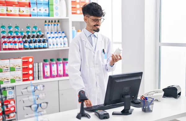 Jovem Hispânico Homem Farmacêutico Segurando Pílulas Garrafa Usando Computador Farmácia — Fotografia de Stock