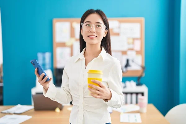 オフィスでスマートフォンのコーヒーを使用して若い中国人女性のビジネスワーカー — ストック写真