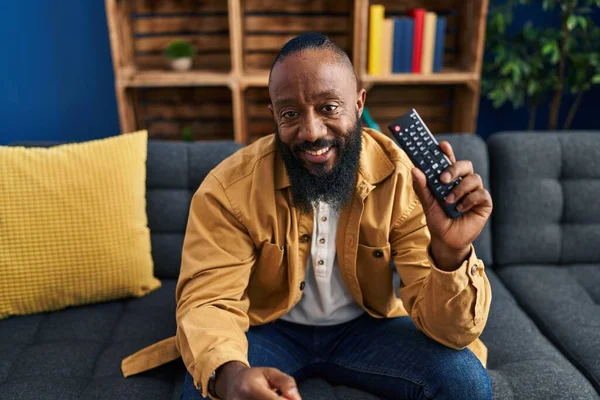 African American Man Holding Television Remote Control Looking Positive Happy — Stock Photo, Image