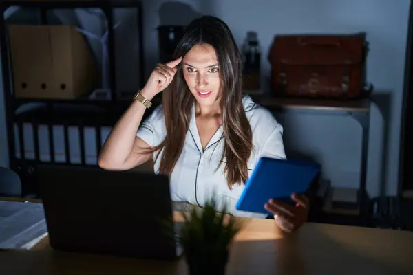 Geceleri Ofiste Çalışan Esmer Bir Kadın Tek Parmağıyla Kafasını Işaret — Stok fotoğraf