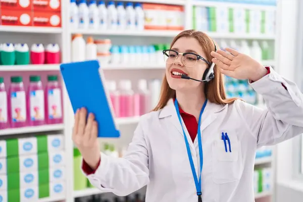 在药店工作的红头发女人用平板电脑打了一个视频电话 她面带微笑地站在那里 面带微笑 脸上带着自信的笑容 — 图库照片