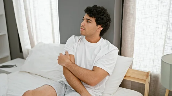 Молодий Латинський Чоловік Подряпає Руку Сверблячки Сидячи Ліжку Спальні — стокове фото
