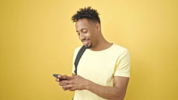 Afričan Američan Nosí Batoh Pomocí Smartphone Přes Izolované Žluté Pozadí — Stock fotografie