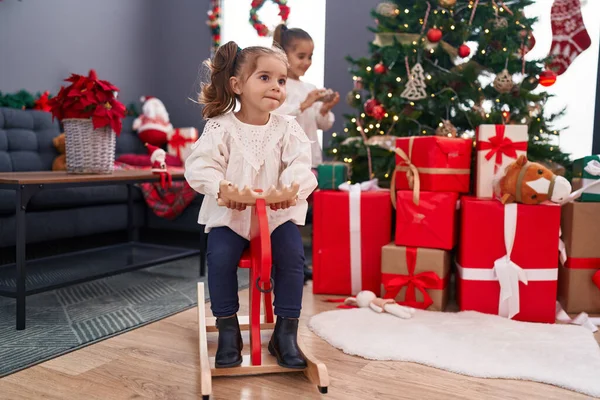 Δύο Παιδιά Παίζουν Τάρανδους Που Λικνίζονται Δίπλα Στο Χριστουγεννιάτικο Δέντρο — Φωτογραφία Αρχείου