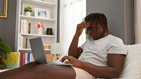 Afrikansk Amerikansk Mann Som Bruker Laptop Sitter Sengen Sliten Soverommet – stockfoto