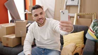 Yeni evindeki kanepede oturan Latin asıllı genç bir adam.