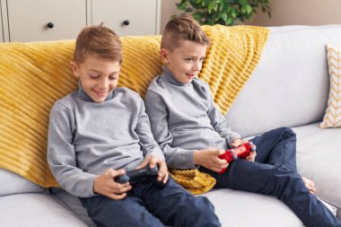 Evdeki kanepede oturup video oyunu oynayan sevimli çocuklar.