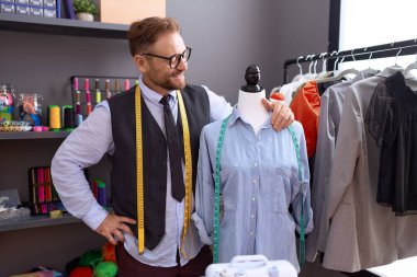 Orta yaşlı bir terzi atölyede kendine güvenen bir manikine gülümsüyor.