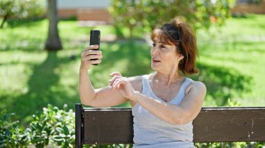 Middle age woman smiling confident having video call at park