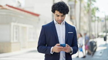 Sokakta akıllı telefon kullanan genç Latin bir iş adamı.