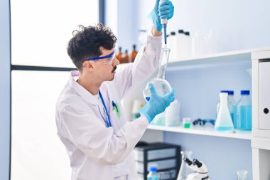Young caucasian man scientist pouring liquid on test tube at laboratory