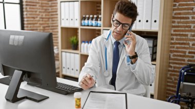 Genç İspanyol doktor klinikte akıllı telefondan konuşuyor.