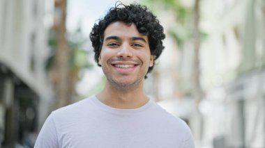 Young latin man smiling confident standing at street