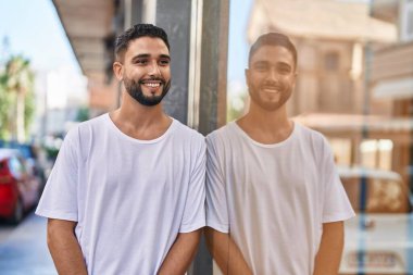 Genç Arap adam gülümsüyor. Kendinden emin. Caddenin kenarına bakıyor.