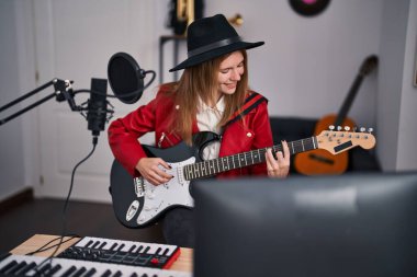 Genç sarışın müzisyen müzik stüdyosunda elektro gitar çalıyor.