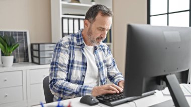 Ofiste çalışan bilgisayar kullanan orta yaşlı bir iş adamı.