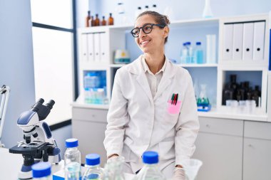 Laboratuvarda çalışan genç bir kadın. Tarafını arıyor. Profil pozu veriyor, doğal bir yüz ve kendine güvenen bir gülümsemeyle.. 