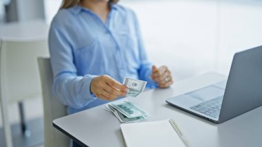 Genç sarışın iş kadını ofiste bilgisayarla dolar sayıyor.