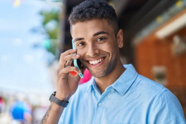African american man smiling confident talking on the smartphone at street market