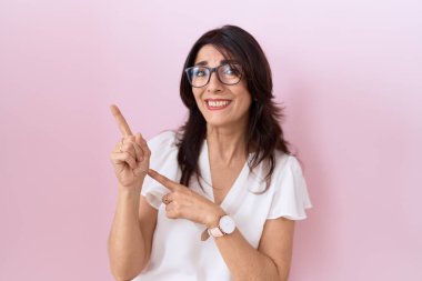 Orta yaşlı, beyaz tişörtlü, gözlüklü, endişeli ve gergin bir kadın. Endişeli ve şaşırmış bir ifade. 