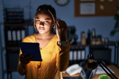 Afrika kökenli Amerikalı kadın, saçları örgülü, tabletle çalışıyor. İtalyan jestleri yapıyor. Elleri ve parmakları kendinden emin bir ifadeyle. 