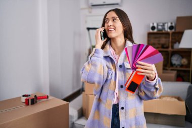 Genç, güzel, İspanyol bir kadın akıllı telefondan konuşuyor. Yeni evinde renk seçiyor.