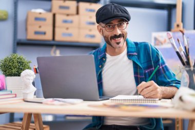 Genç İspanyol ressam sanat stüdyosunda dizüstü bilgisayarla çizim yapıyor.