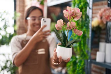 Genç, güzel, İspanyol bir çiçekçi çiçekçiye akıllı telefondan fotoğraf dikmiş.