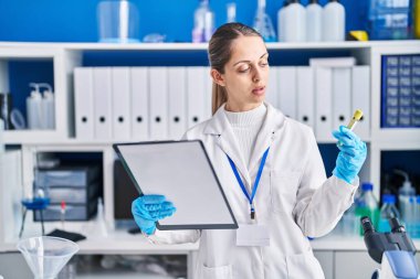 Laboratuvarda elinde deney tüpü tutan genç bilim kadını.