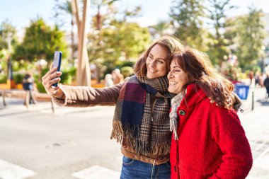 Two women mother and daughter make selfie by smartphone at park