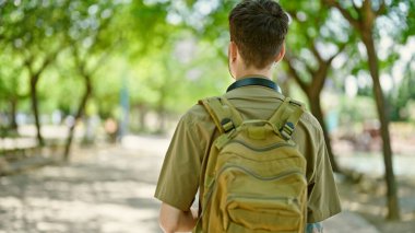 Sırt çantalı genç İspanyol turist parkta ters duruyor.
