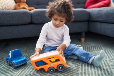 Sevimli İspanyol kız evde yerde oturmuş oyuncaklarla oynuyor.