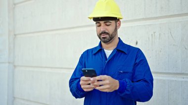 İnşaat alanında akıllı telefon kullanan İspanyol işçi.