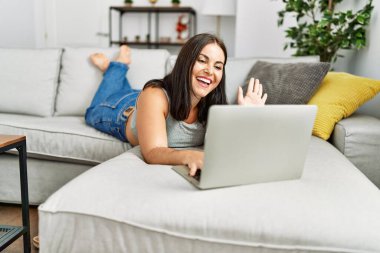 Genç, güzel İspanyol bir kadın evdeki kanepede uzanmış video görüşmesi yapıyor.