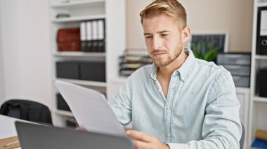 Young caucasian man business worker using laptop reading document at office