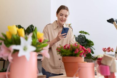 Genç beyaz kadın çiçekçi çiçekçiye akıllı telefondan fotoğraf dikmiş.