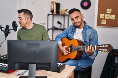 Two men musicians singing song playing piano and classical guitar at music studio