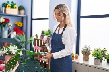 Çiçekçide çalışan sarışın bir çiçekçi.