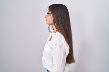 Genç, esmer, gözlüklü bir kadın yan tarafa bakıyor, rahat bir poz veriyor ve kendine güvenen bir gülümseme takınıyor.. 