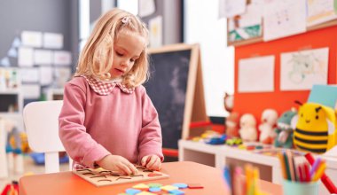 Anaokulunda matematik bilmecesiyle oynayan sevimli sarışın kız.