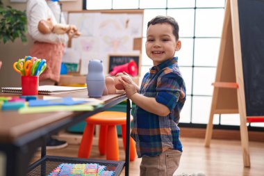 Anaokulunda masada oturan sevimli İspanyol çocuk oyuncaklarla oynuyor.