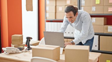 Ofiste çalışan bir dizüstü bilgisayar kullanan orta yaşlı bir iş adamı.