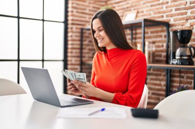 Genç ve güzel İspanyol kadın evde dolar sayıyor.