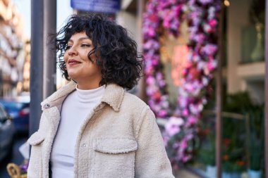 Young beautiful hispanic woman smiling confident looking to the side at street
