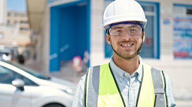 Kafkasyalı genç mimar inşaat alanında kendine güvenerek gülümsüyor.
