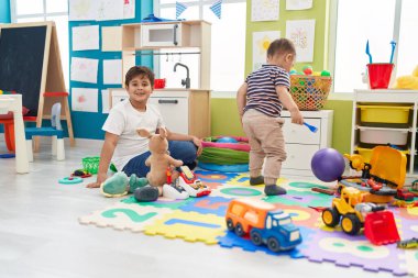 Anaokulunda yerde otururken kendine güvenen sevimli çocuklar.